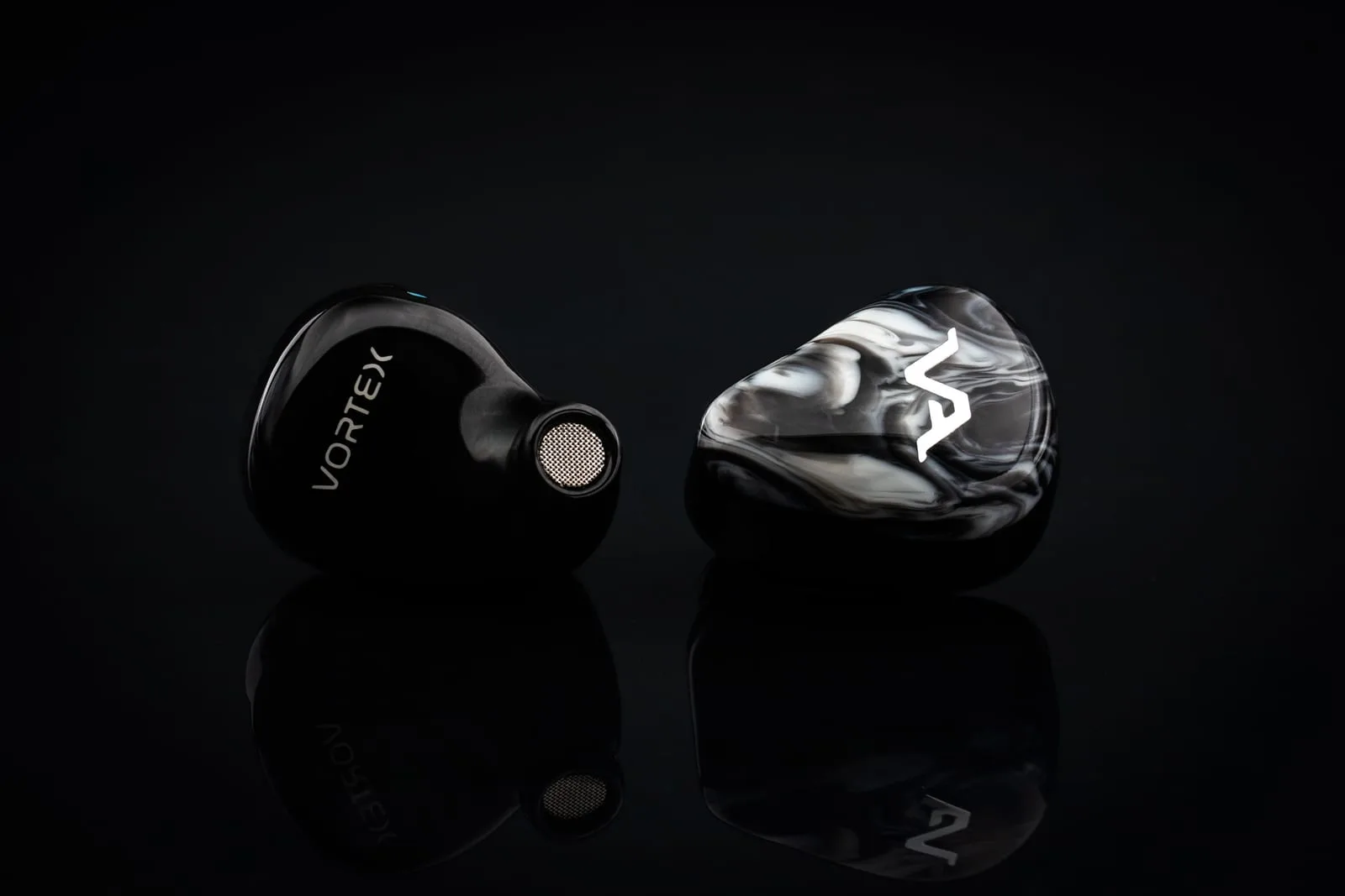 Virtus Audio Vortex — pair standing face to back, showing the monochrome swirl faceplate and the engraved shell